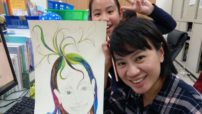 邱曉詩與學生合影，手上拿著她的自畫像。