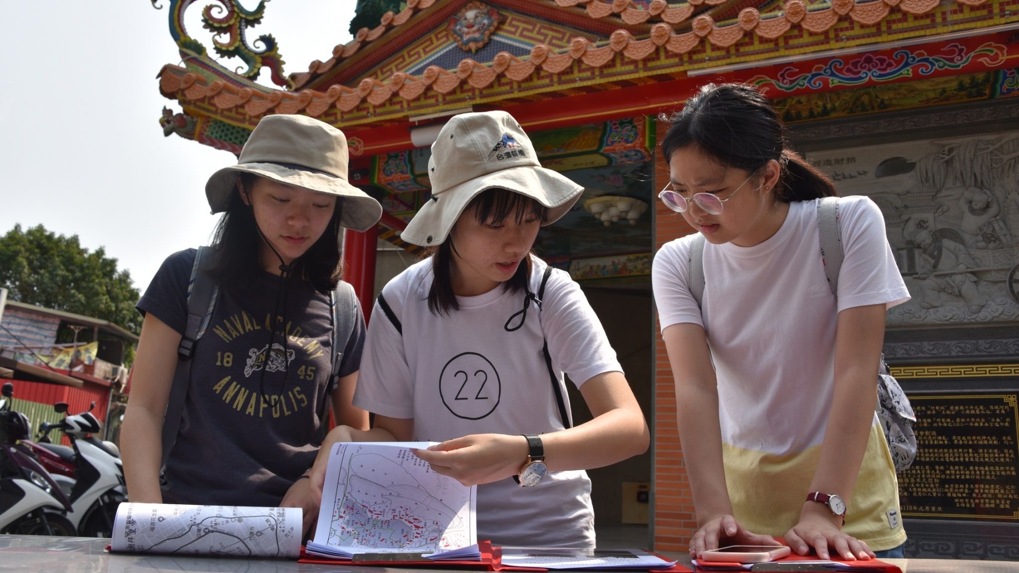 培訓期間選手到新竹進行實地考察，梅立昀（中）、莊千逸（右）研究手中的題目與地圖， 和成員找尋任務指定的廟宇及門牌。台灣師範大學地理學系提供。