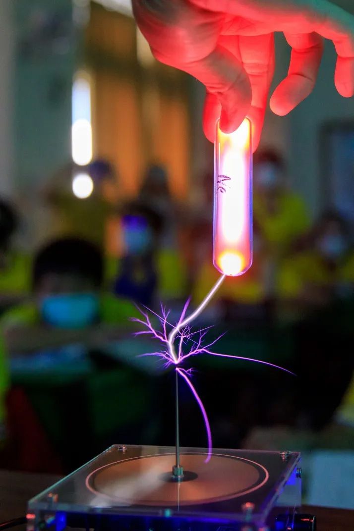 蘇宥誠拿出特斯拉線圈產生高壓電弧，使添加惰性氣體的玻璃管發出特殊色光，讓同學一陣驚呼。（邱劍英攝）